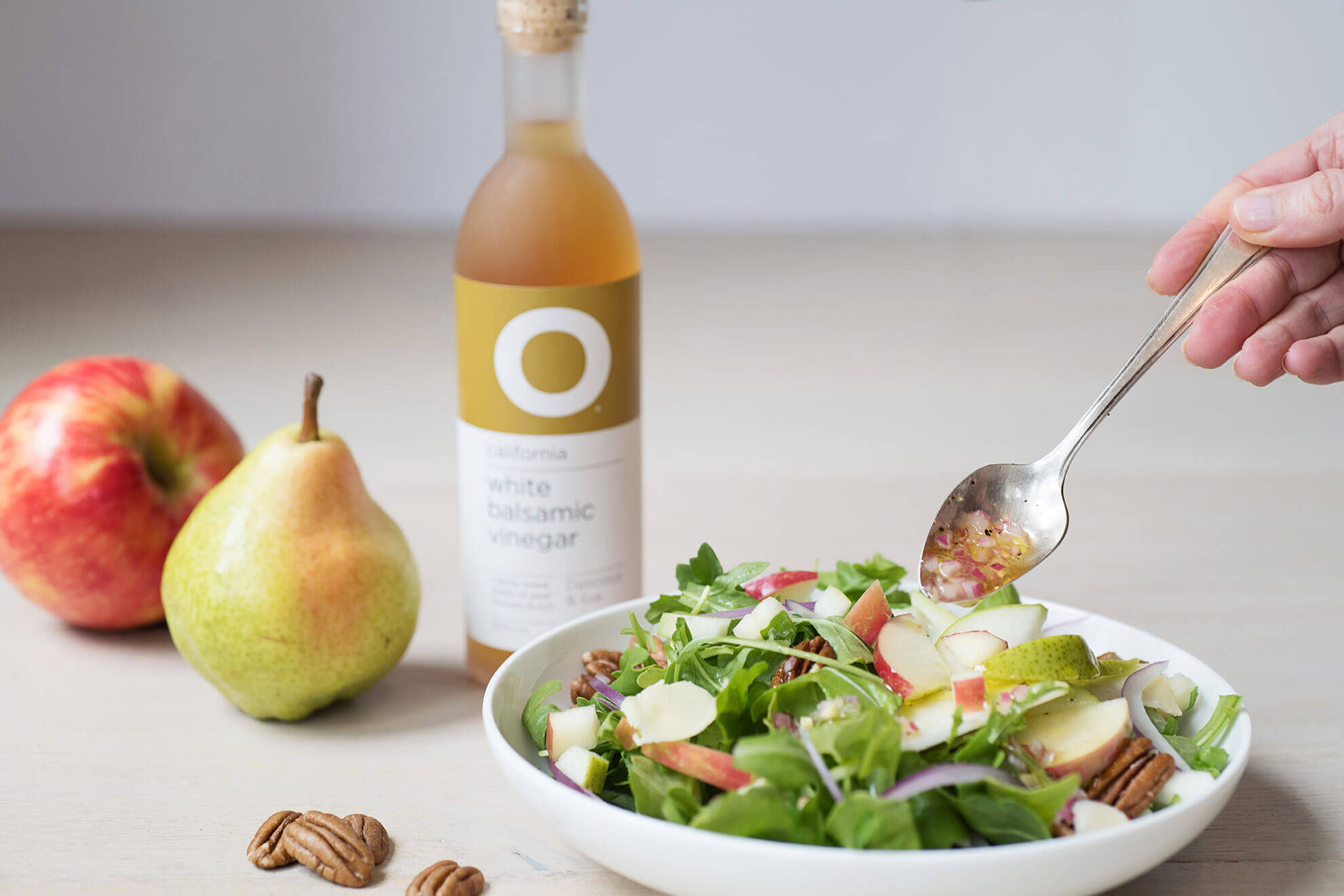 O Olive Oil White Balsamic Vinegar bottle desgin next to salad.