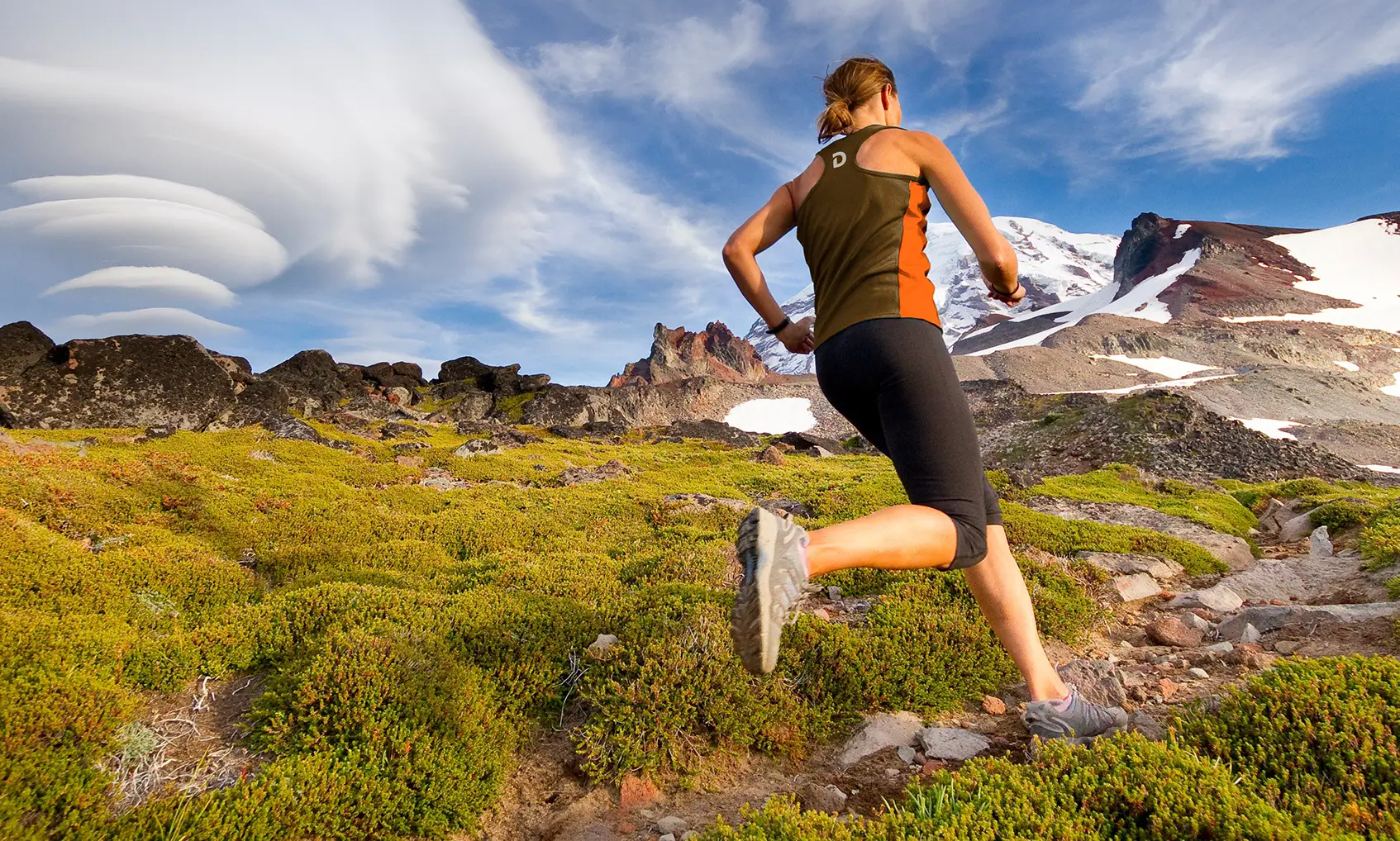 Detour protein bar brand lifestyle photography style, featuring female runner going up mountain trail.